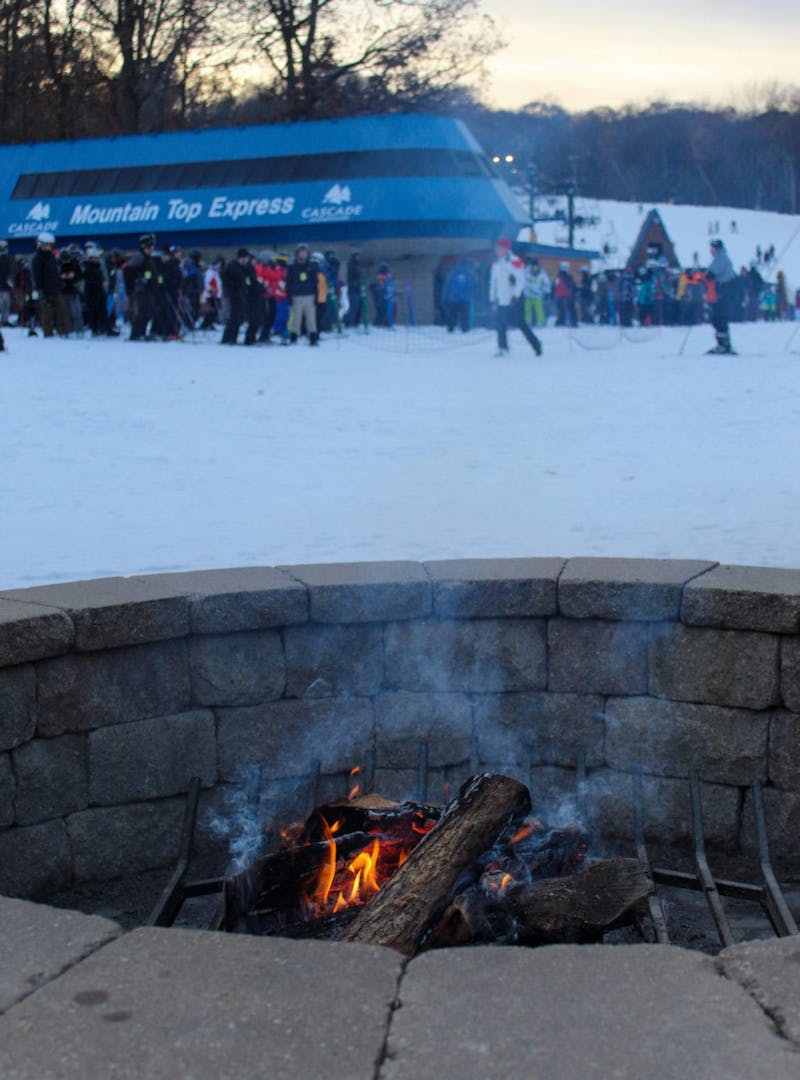 Fire pit at the base of ski hill, with ski lift line in the background