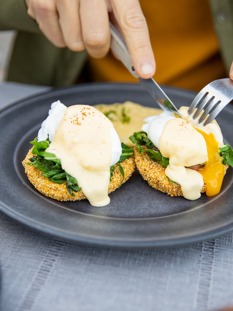 Yolk oozing out of an egg on top of fried green tomatoes. 