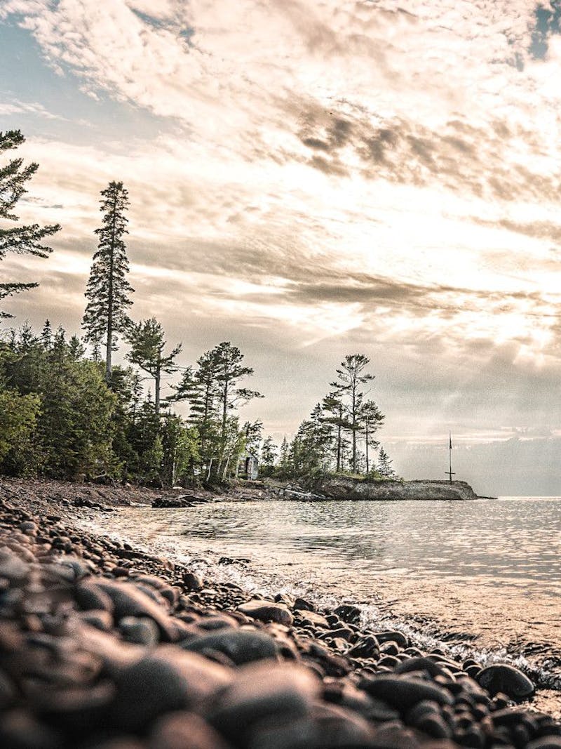 Sun shining over a like with a rocky shore