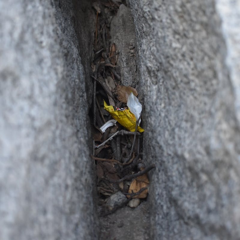 Piece of yellow trash hidden within two rocks