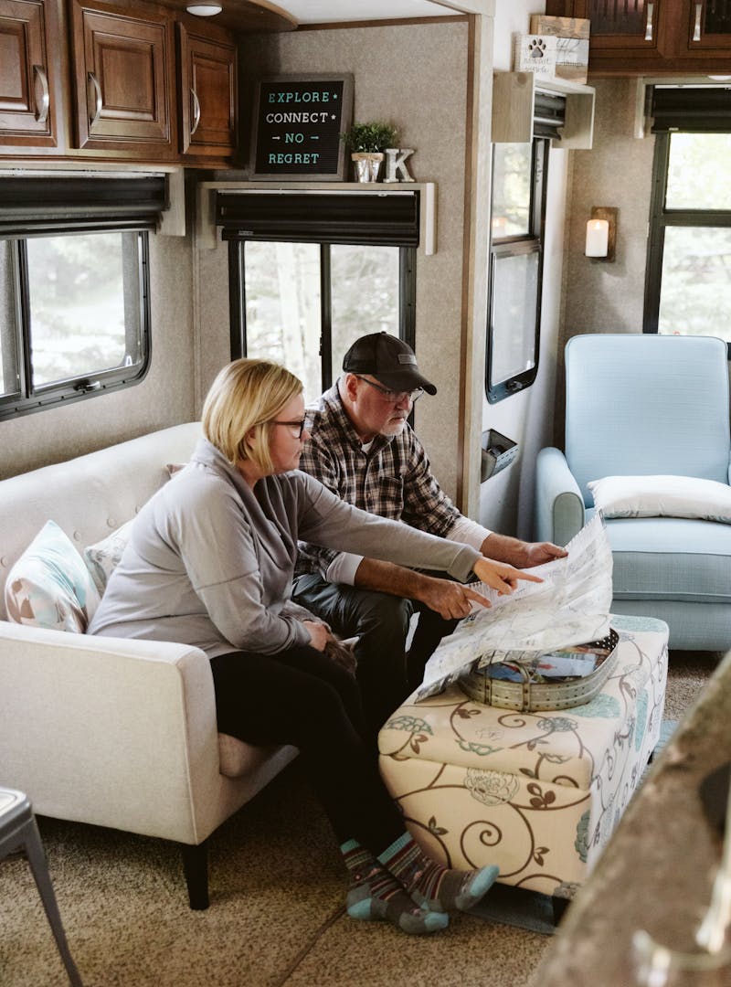 Tina and Craig sitting on a couch inside their RV, looking at a map.