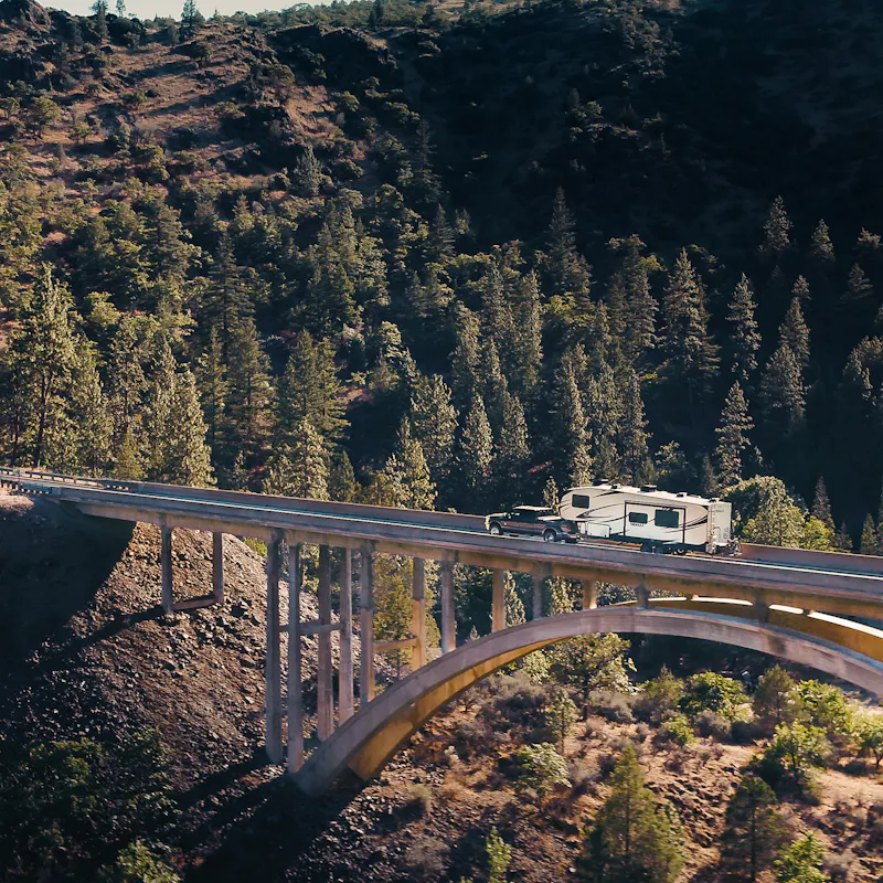 A fifth wheel RV driving across a bridge.
