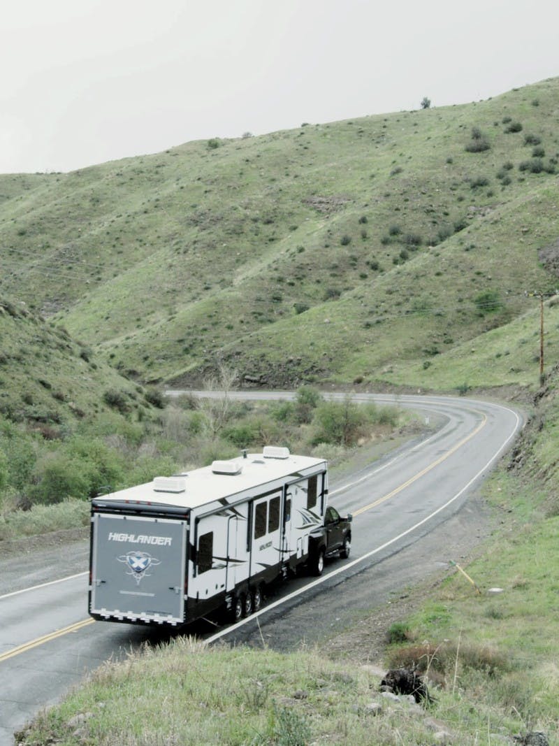 A Highland Toy Hauler RV driving on the road through the mountains.