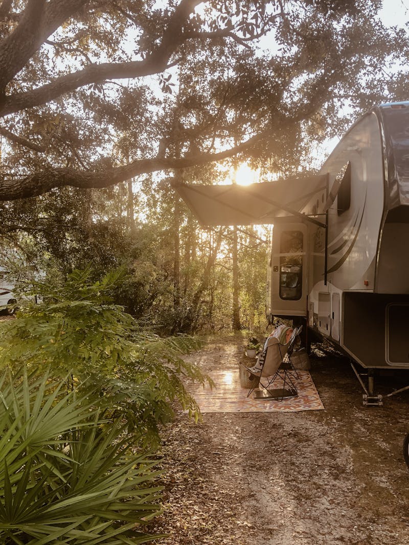 Shannon Carew's Highland Ridge RV parked at a leafy campsite.