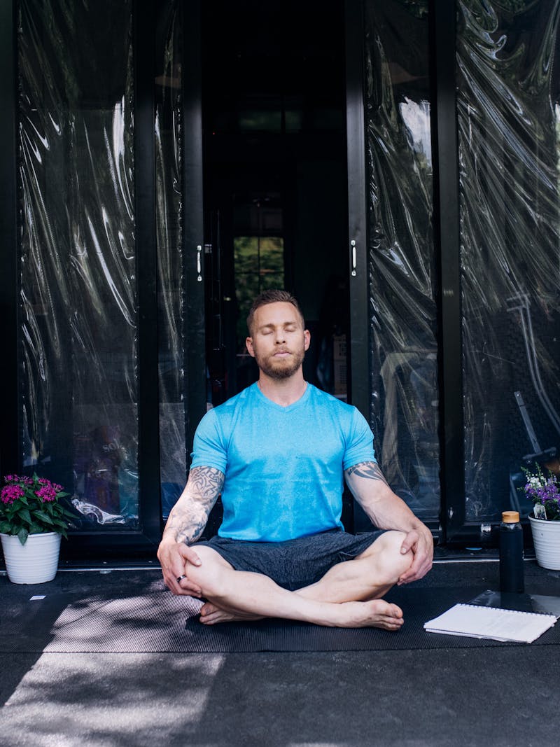 A well-muscled man meditating on the porch of a toy hauler RV.