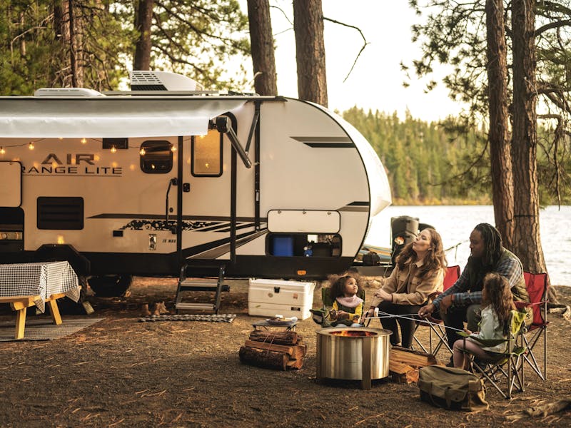 A family makes smores outside of a travel trailer