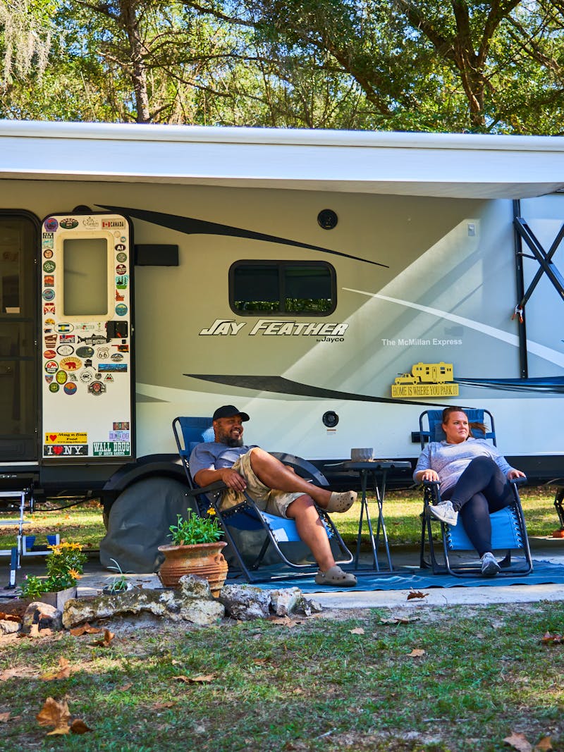 Ben and Christina McMillan lounging in front of their Jay Feather travel trailer