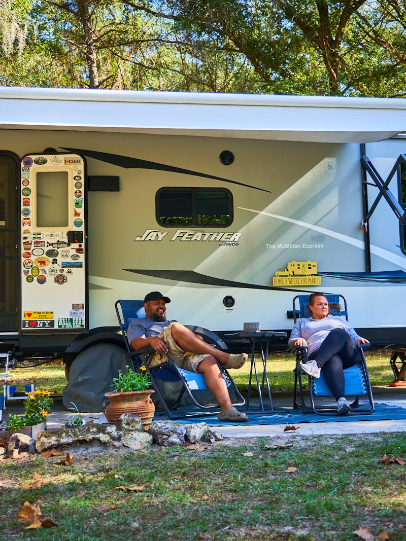 Ben and Christina McMillan lounging in front of their Jay Feather travel trailer