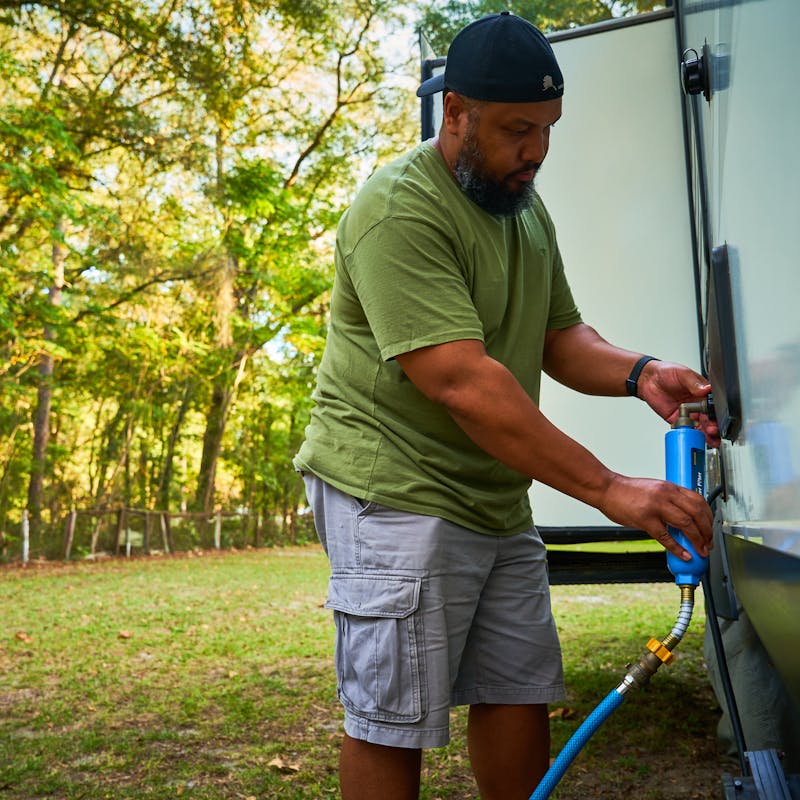 Ben McMillan connecting a water hose to his RV