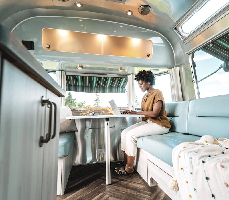 a woman working on a laptop inside of an Airstream travel trailer
