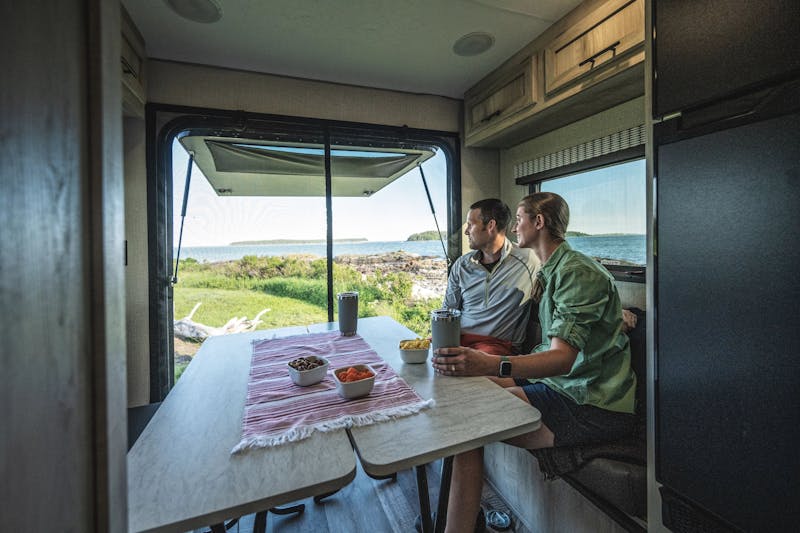 A couple enjoys the view from the dinnette of a KZ Escape travel trailer