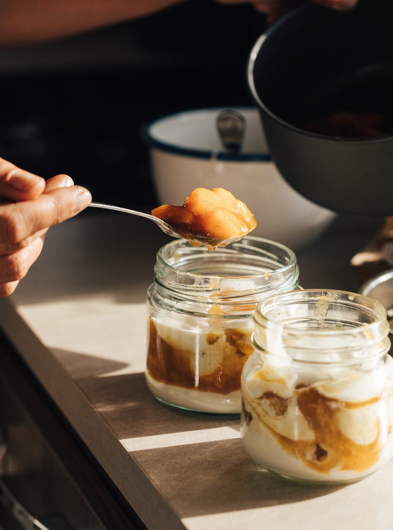 Layering apricot sauce with plain yogurt in a pretty, clear jar.