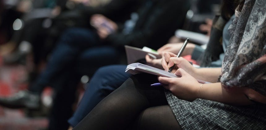 Men and women taking notes during business seminar