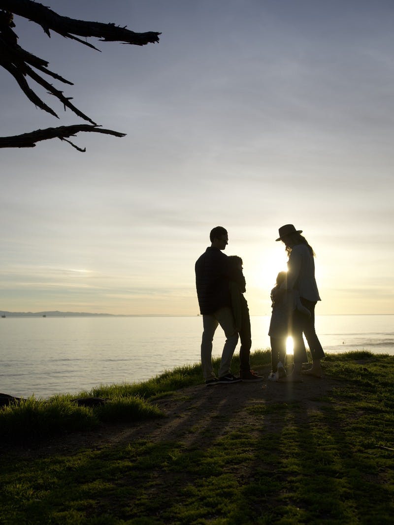 Image of Sarah Schultz and her family overlooking the ocean from a clifftop during a sunset.