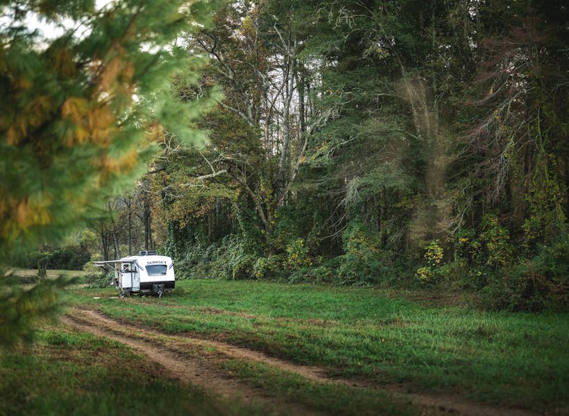 An travel trailer RV parked in a green field.