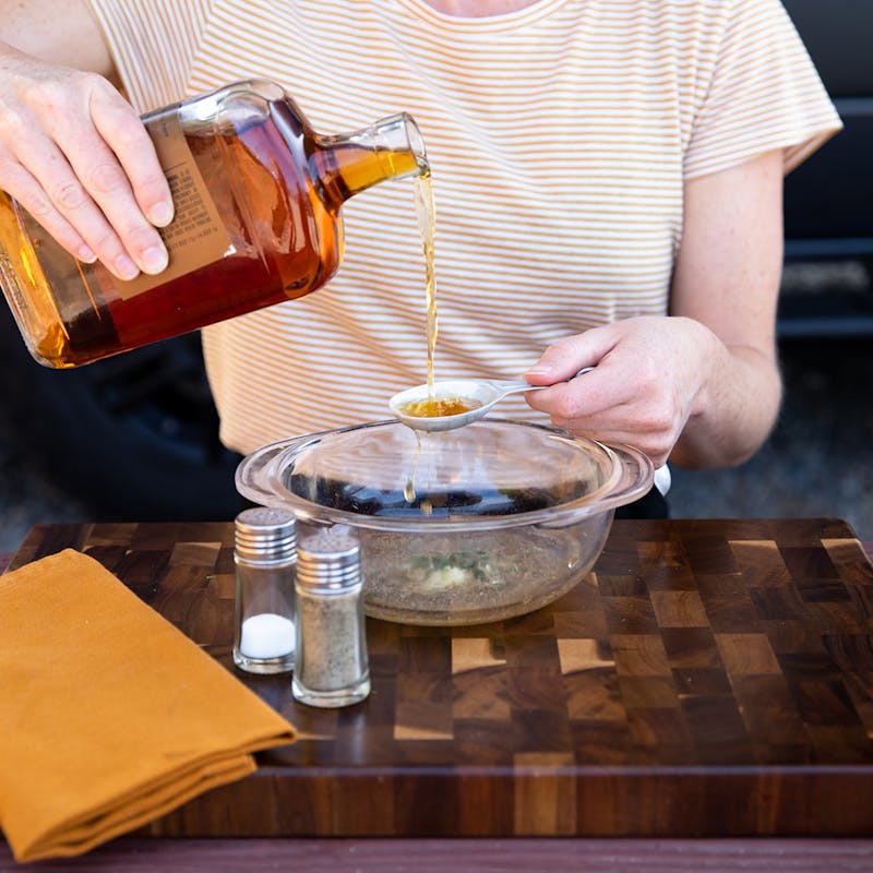 A woman pours whiskey into a measuring spoon.