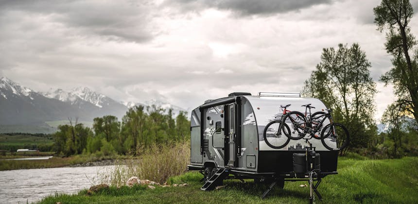 A venture sonic rv camping near a river with two bikes on a bike rack