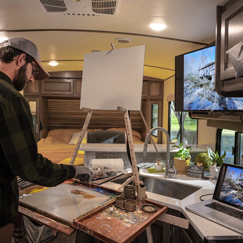 Todd Schabel paints a landscape inside of his RV.
