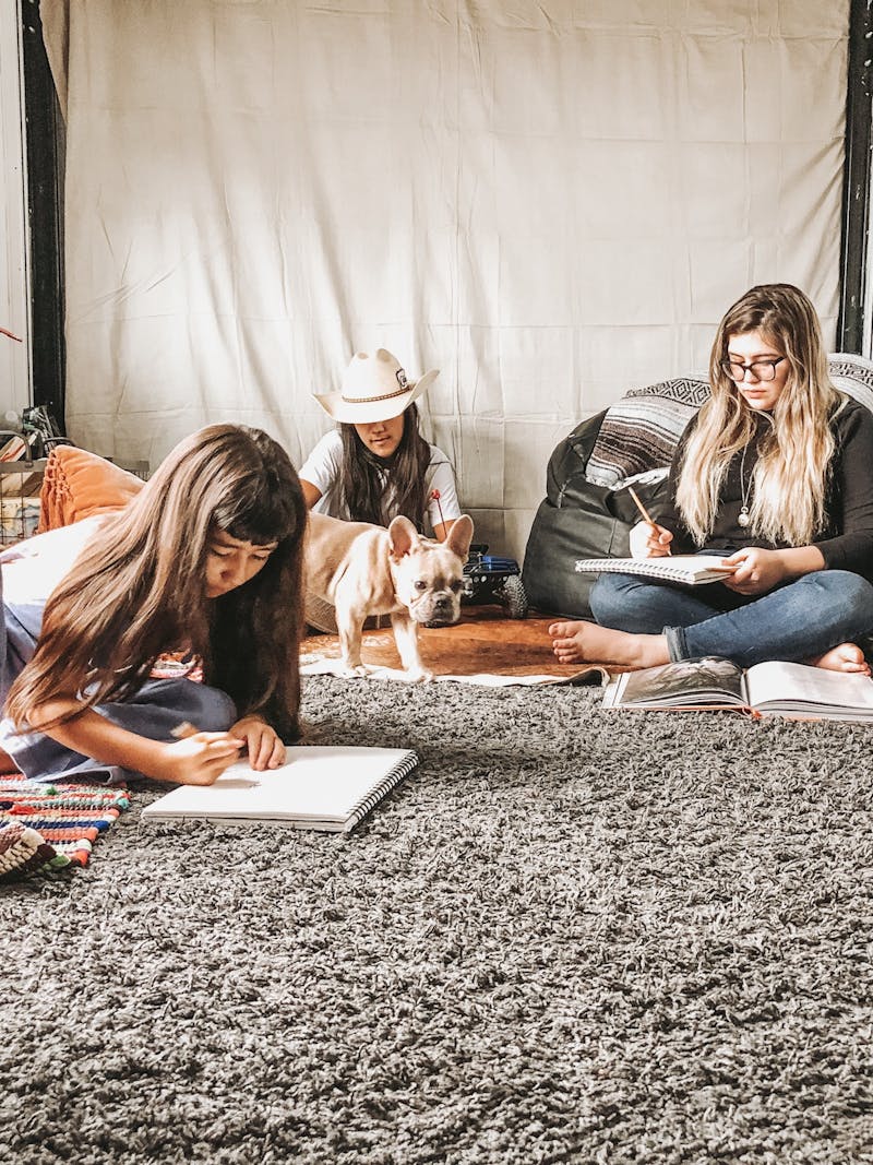 Three kids and a dog sitting in a cozy room in an RV.