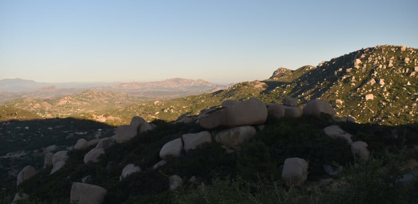 The sun setting over rocky hills.