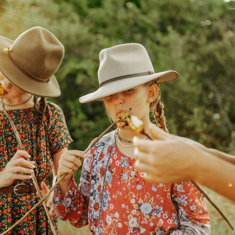 Girls eating shrimp cooked on sticks