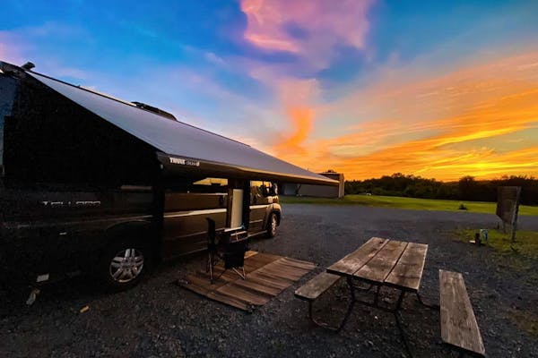 Jess Lawson's Thor Motor Coach Tellaro with the awning out facing a beautiful sunset.