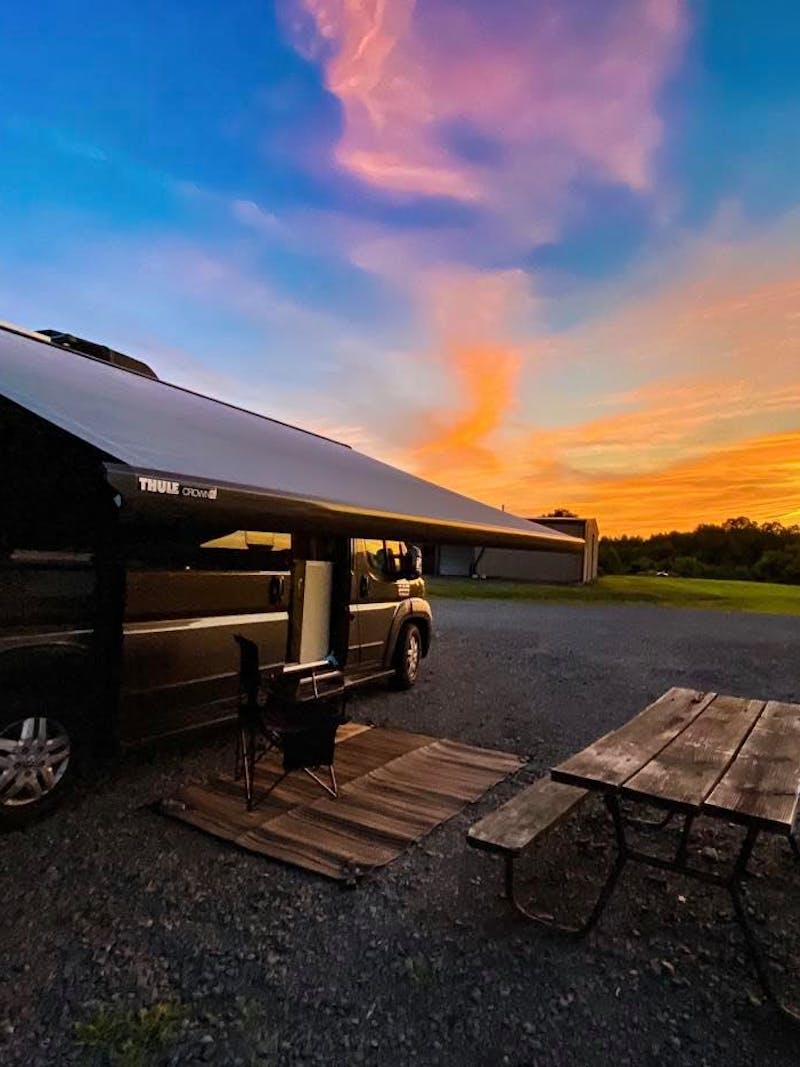 Jess Lawson's Thor Motor Coach Tellaro with the awning out facing a beautiful sunset.