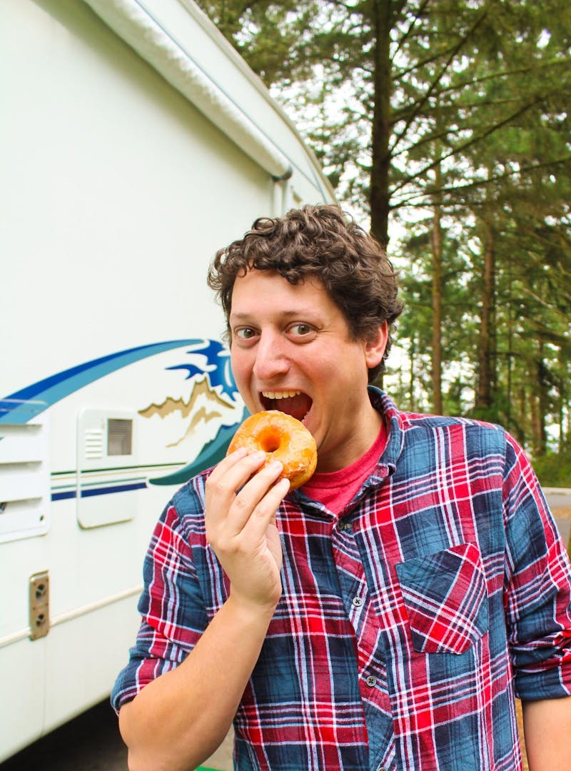 Jesse Lyons about to take a bite of a donut in front of his Keystone Cougar.