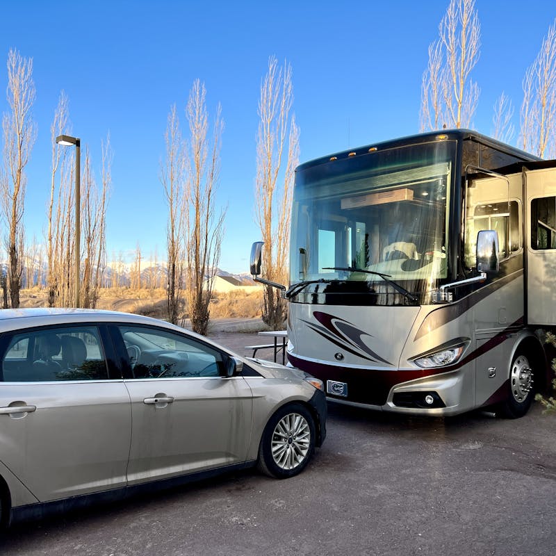 Laura Georgieff's Tiffin Phaeton and small sedan parked at a campground spot