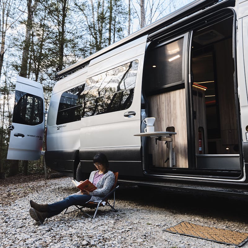 Kathy Karlo reading outside of an Airstream Camper Van