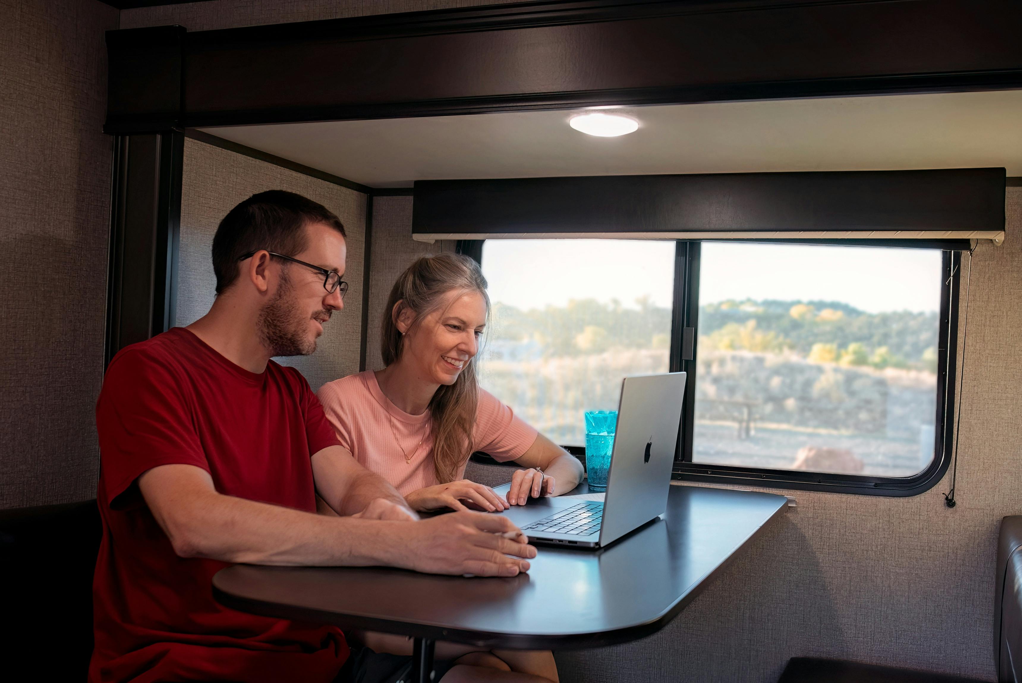 Alison and Jason Takacs sitting at the table with their laptop inside their Jayco Jay Flight