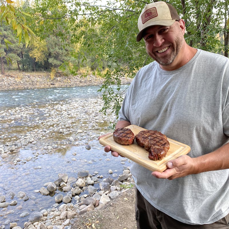 Abby Booth's husband holds a cutting board with steaks.