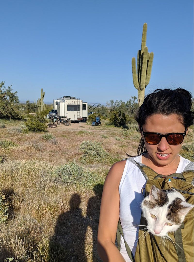 Brittany Ciepluch holding her cat in her backpack while going on a hike near their Keystone Montana fifth wheel.