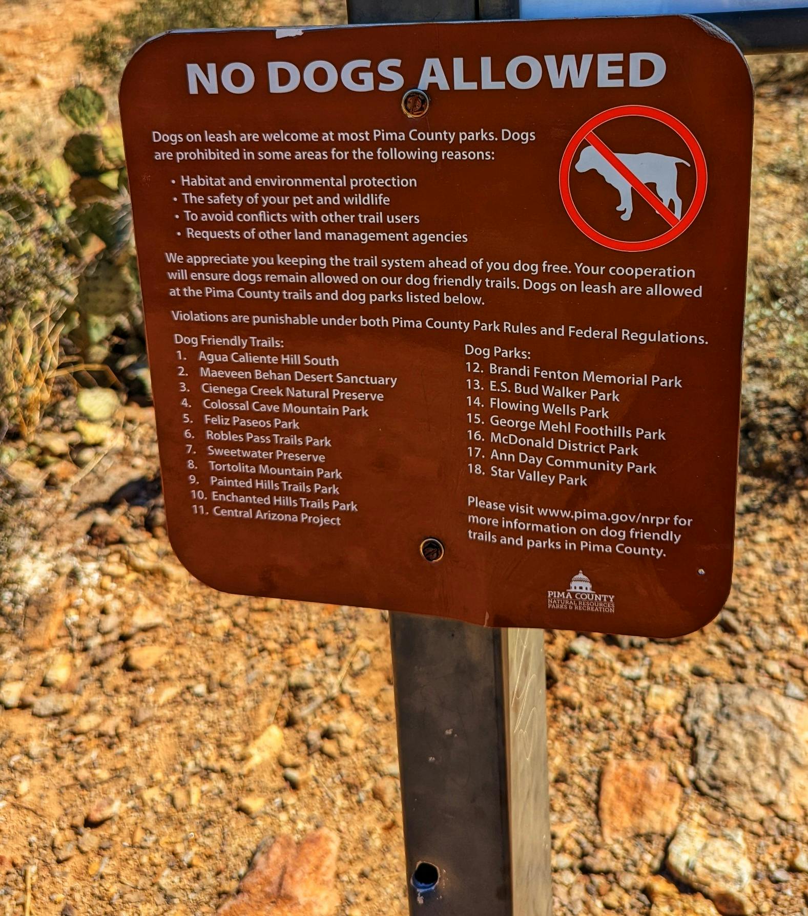 DUSTIN & SARAH BAUER show a no dogs allowed sign on a trail
