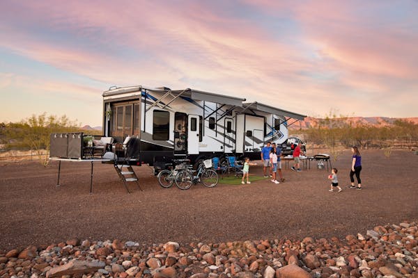 Robin, Warren and their family play outside of their Keystone Fuzion toy hauler RV.
