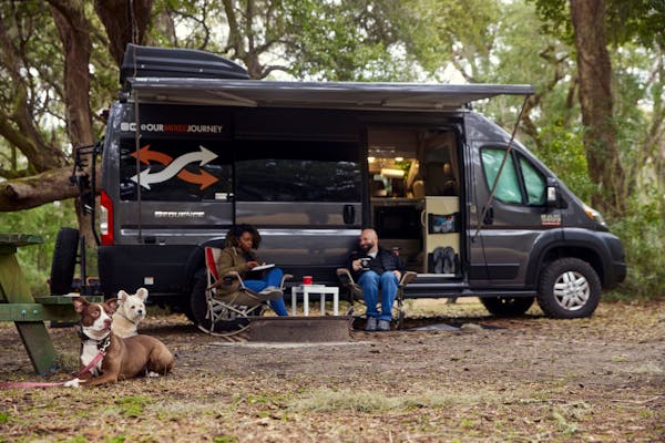 Gabe and Rocio Rivero sitting outside their RV with their two dogs