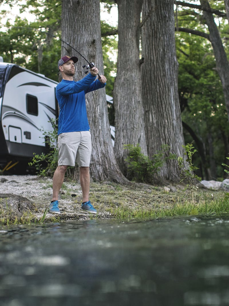 Robert Field fishes in a lake with his Keystone Cougar parked behind him.