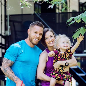 A portrait of Lauren and Fraser Bayley with their daughter and one of their dogs.