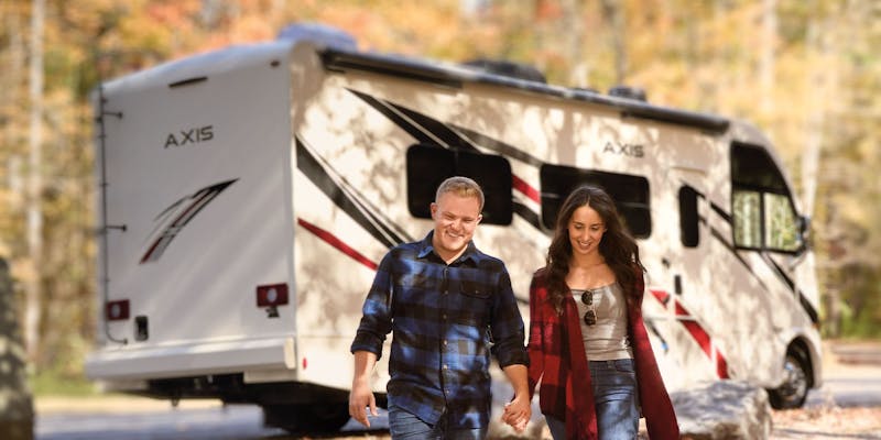 2022 Thor Axis Class A Motorhome slider image lifestyle leaves couple exiting for a stroll