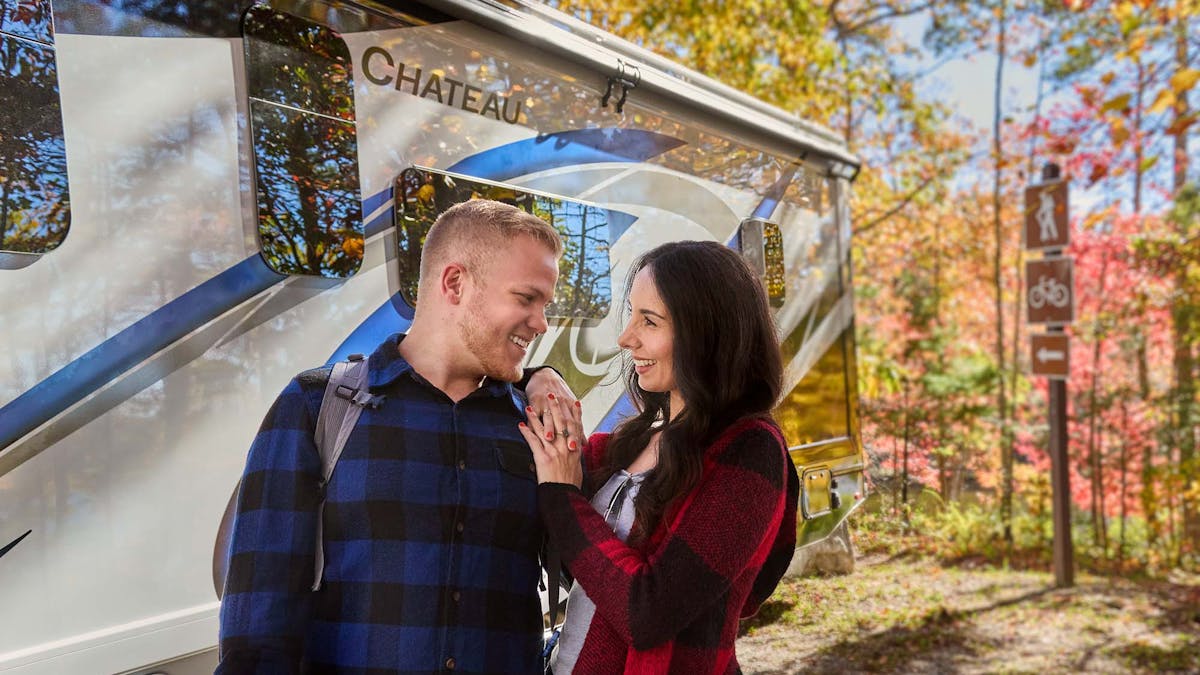 Chateau Class C RV Midnight Blue style in Tennessee with couple standing under fall leaves
