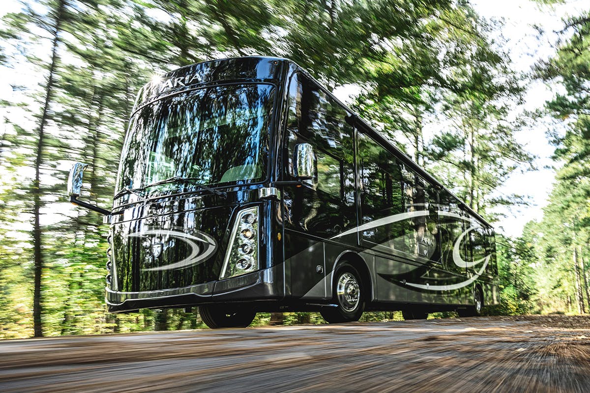 2022 Thor Aria Class A Diesel Pusher RV driving in scenic wooded area