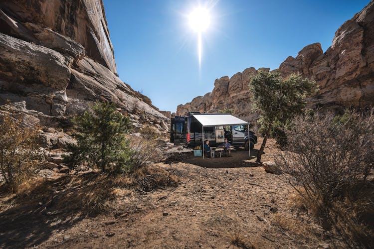 2022 Thor Sanctuary Mercedes Sprinter Van Lifestyle corporate photo shoot in Utah guys sitting under awning outside boondocking at campsite