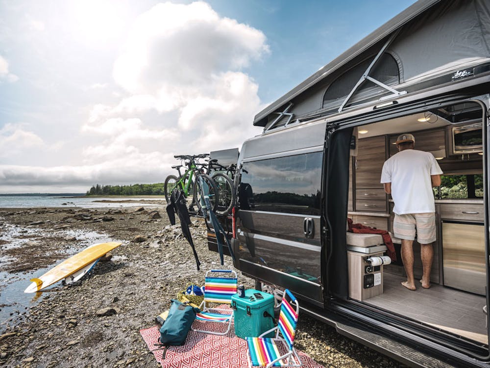 2022 Thor Scope Class B RV Camper Van Lifestyle Maine Corporate photo shoot Thule bike rack on rear door with entry door open and SkyBunk® Sky Bunk Pop Top extended key feature