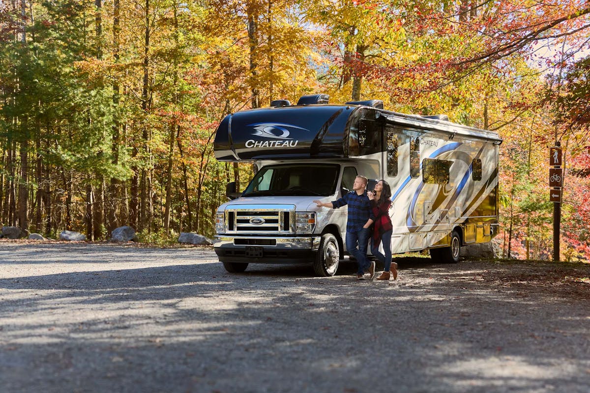 Chateau Class C RV Midnight Blue style in Tennessee with couple standing under fall leaves