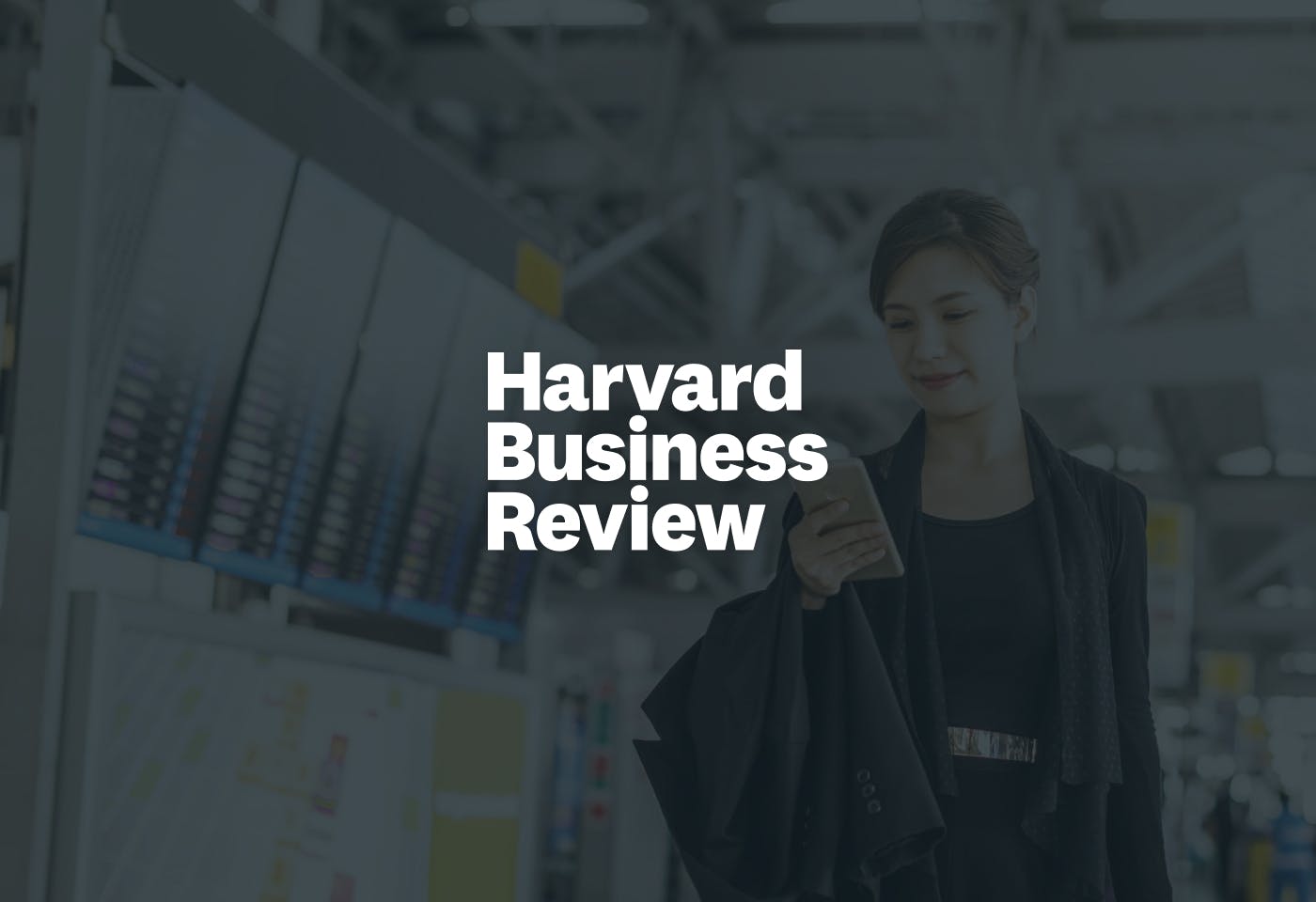The Harvard Business Review logo overlaid over a woman holding a phone and walking through an airport.