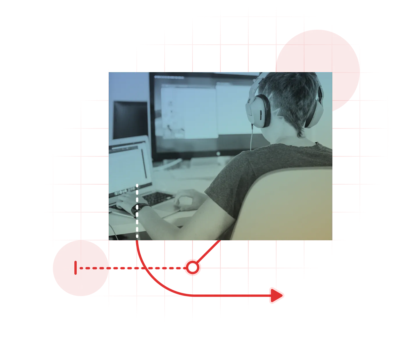 Looking over the shoulder of a person sitting at their desk while working with headphones on.