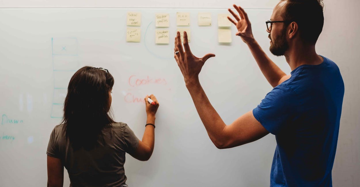 Teammates brainstorming and writing ideas on a whiteboard