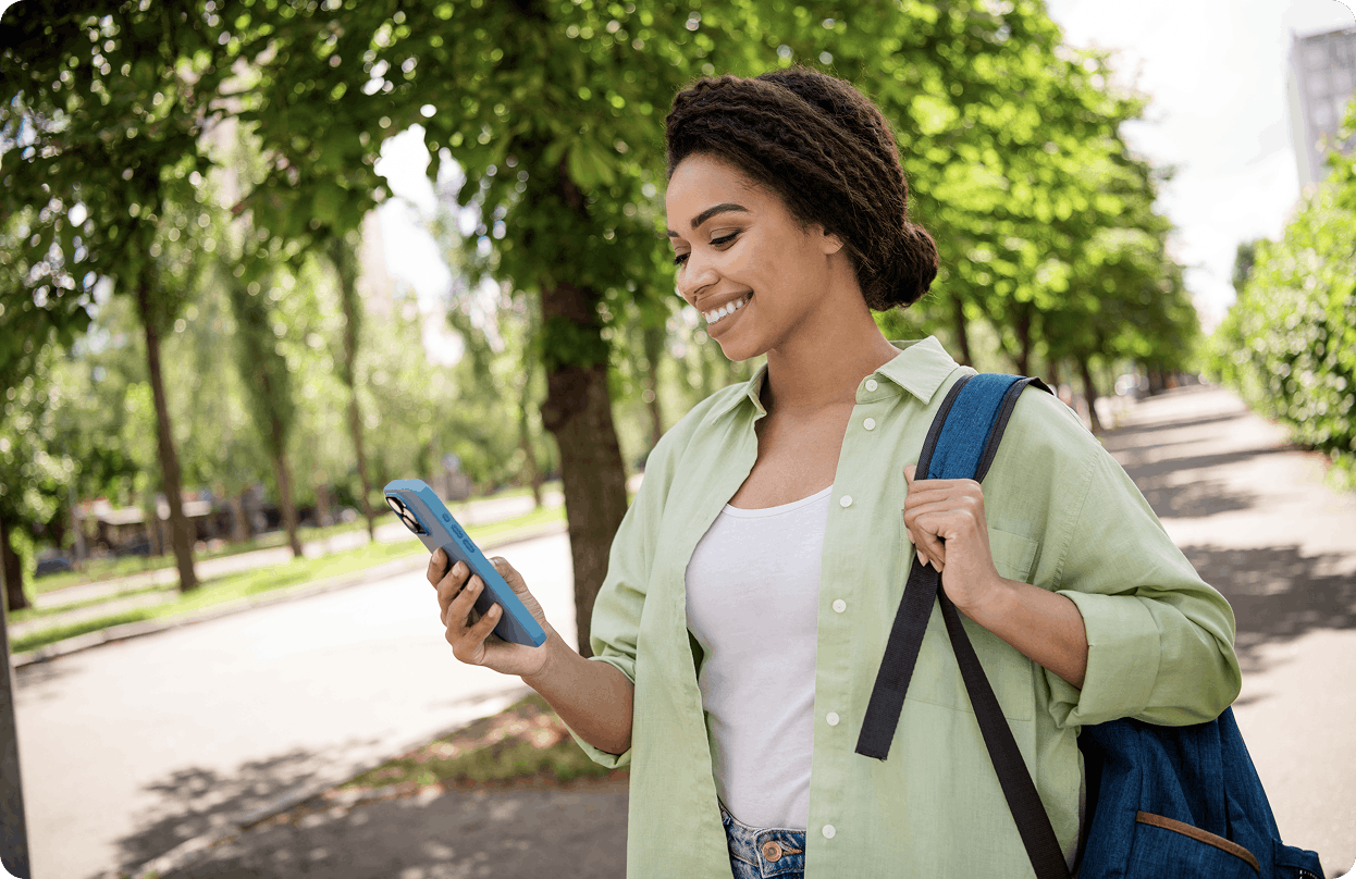 A woman looking at her phone and wearing a backpack