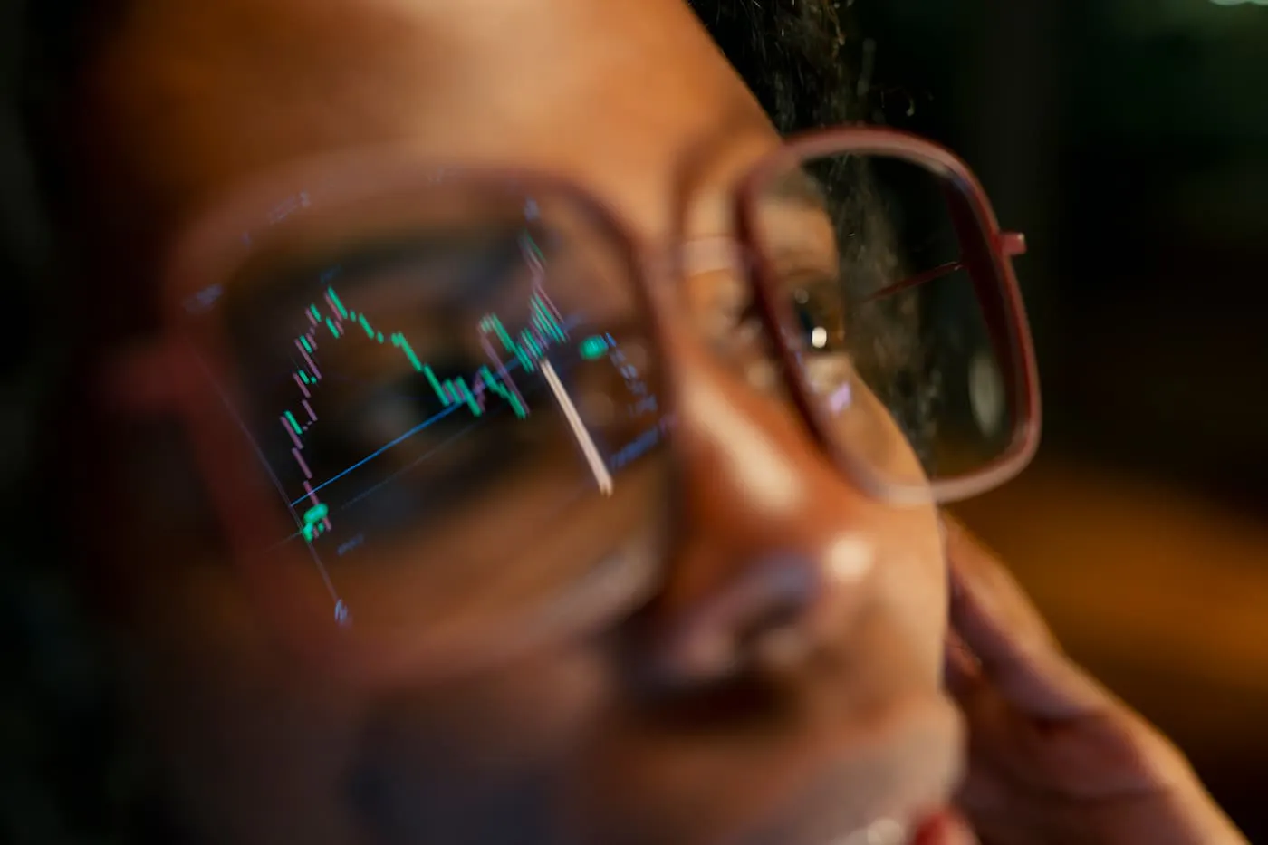 A closeup of a person's face wearing glasses. A fever line chart in green and red is reflected in their glasses.