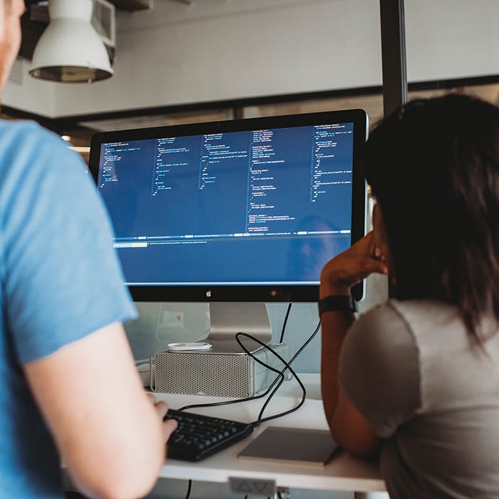 Developers working together at a desk pairing on a problem